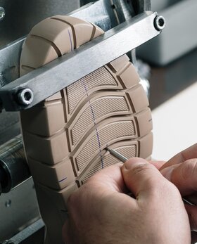 Zwei Hände prüfen die Sohle eines Schuhs in einer Maschine. | © Gabor Shoes GmbH, Rosenheim