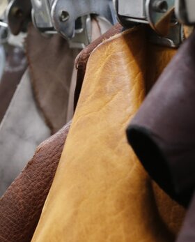 Mehrere unterschiedlich gefärbte Lederstücke hängen sortiert an Metallklemmen in einer Reihe. | © Gabor Shoes GmbH, Rosenheim