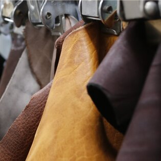 Flera läderbitar i olika färger hänger sorterade i rad med metallklämmor. | © Gabor Shoes GmbH, Tyskland