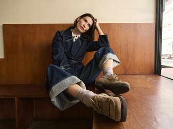 Una donna è sdraiata sul pavimento e indossa una ballerina intrecciata in pelle marrone scuro, abbinata a jeans scuri. Il focus è sulla scarpa. | © Gabor Shoes GmbH, Germania