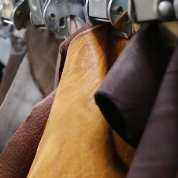 Mehrere unterschiedlich gefärbte Lederstücke hängen sortiert an Metallklemmen in einer Reihe. | © Gabor Shoes GmbH, Rosenheim