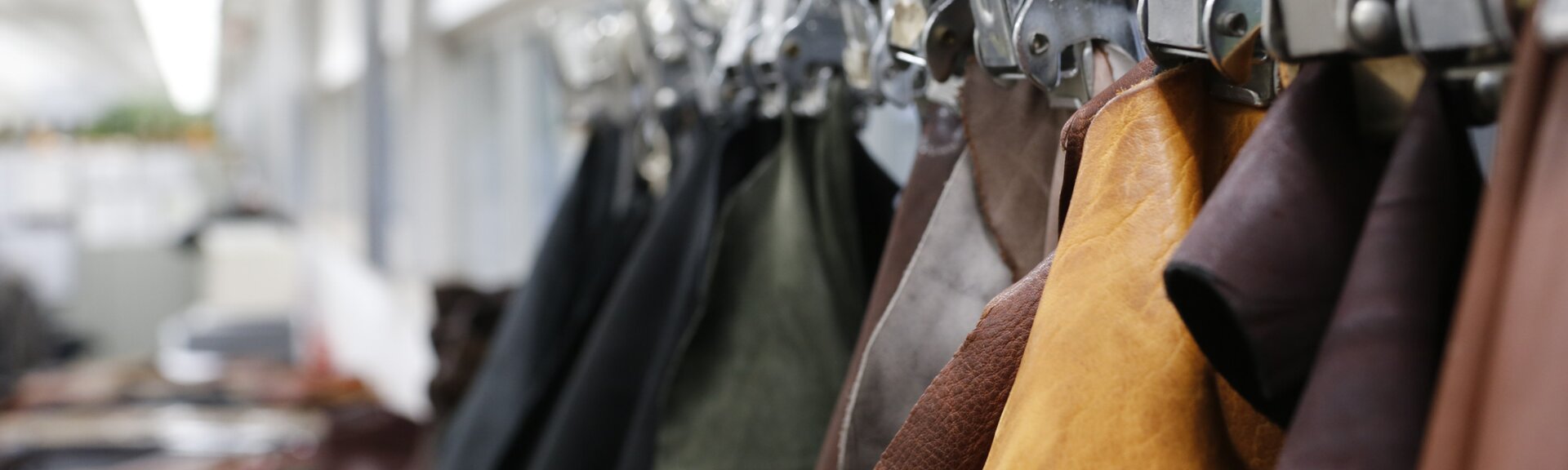 Mehrere unterschiedlich gefärbte Lederstücke hängen sortiert an Metallklemmen in einer Reihe. | © Gabor Shoes GmbH, Rosenheim