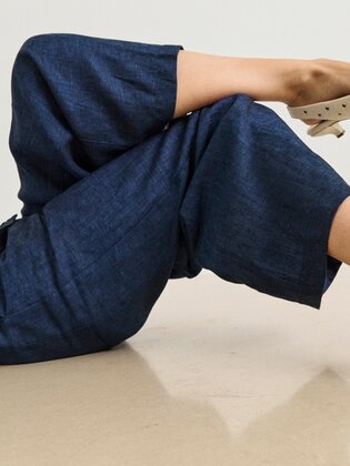 En kvinna har på sig en mörkblå jumpsuit och ligger avslappnat på golvet. De beige pumpsen med små silvernitar och låg klack är bildens fokus. | © Gabor Shoes GmbH, Tyskland