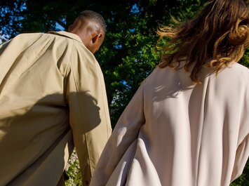 Twee personen in lichte jassen wandelen buiten in het groen. | © Gabor Shoes GmbH, Duitsland
