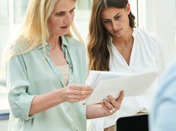 Zwei Personen schauen gemeinsam auf Unterlagen. | © Gabor Shoes GmbH, Rosenheim