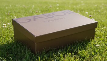 Braune Gabor-Schuhschachtel steht auf grünem Rasen. | © Gabor Shoes GmbH, Rosenheim