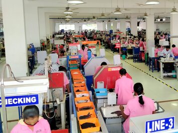 Viele Mitarbeitende arbeiten in einer großen Produktionshalle an Maschinen und Fließbändern. | © Gabor Shoes GmbH, Rosenheim