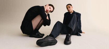 Gabor Damenschuhe | Ein Mann und eine Frau sitzen lässig am Boden und tragen schwarze Herren-Sneaker und schwarze Damen-Loafer - Herbst/Winter 2026 | © Gabor Shoes GmbH, Rosenheim