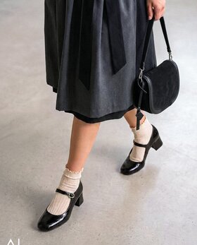 Gabor Damenschuhe | Frau im Dirndl trägt elegante schwarze Gabor Spangenpumps mit hellen Socken, kombiniert mit schwarzer Schultertasche. | © Gabor Shoes GmbH, Rosenheim