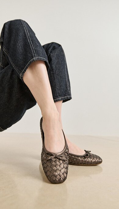 Gabor Damenschuhe | Zwei geflochtene braune Damen-Ballerinas mit Schleife, getragen von einem Model in dunkler Jeans. | © Gabor Shoes GmbH, Rosenheim